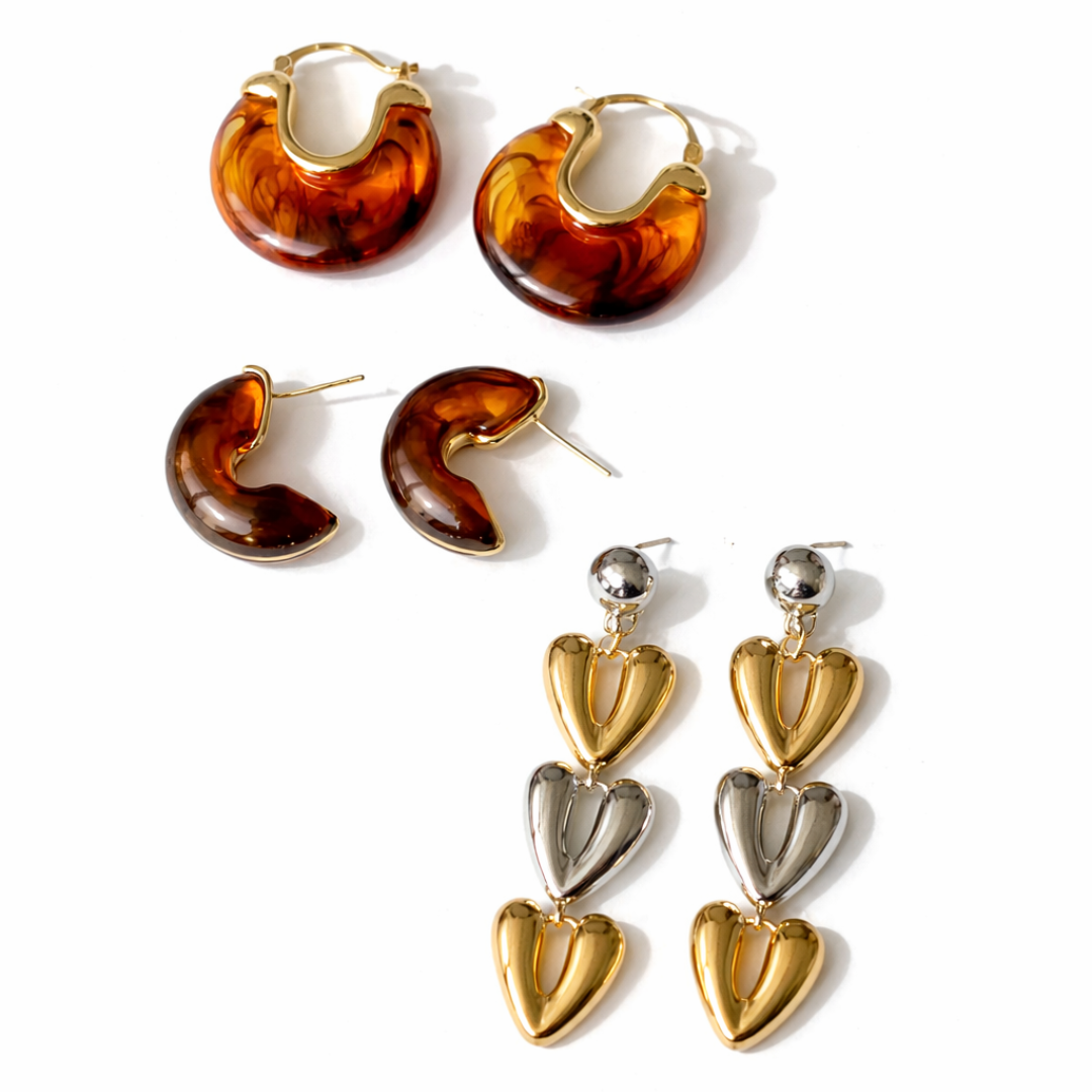 Warm amber tone earring stack with glossy resin hoops and bold triple heart gold earrings
