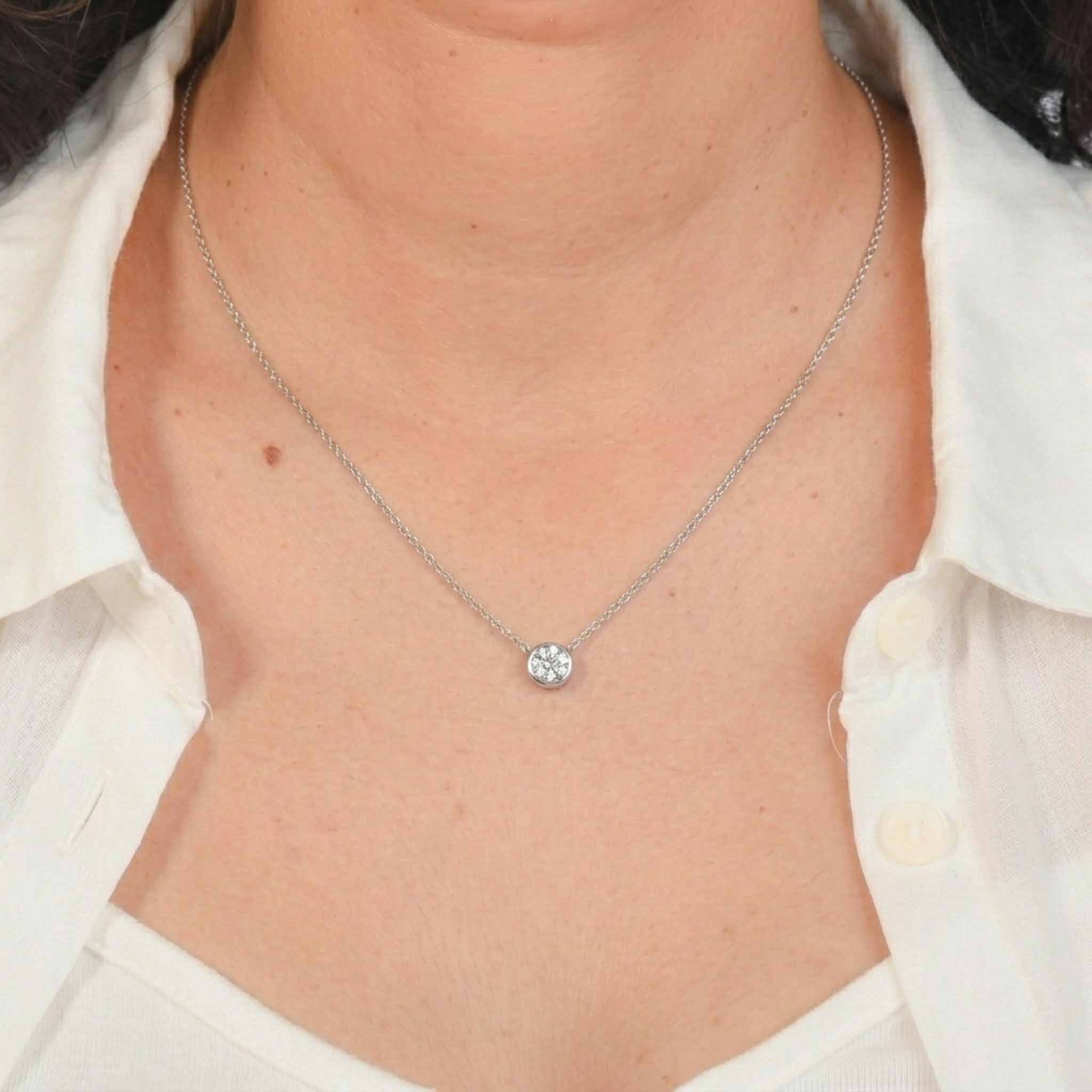 Silver solitaire pendant necklace worn on neck, featuring a round-cut crystal in a bezel setting on a delicate chain