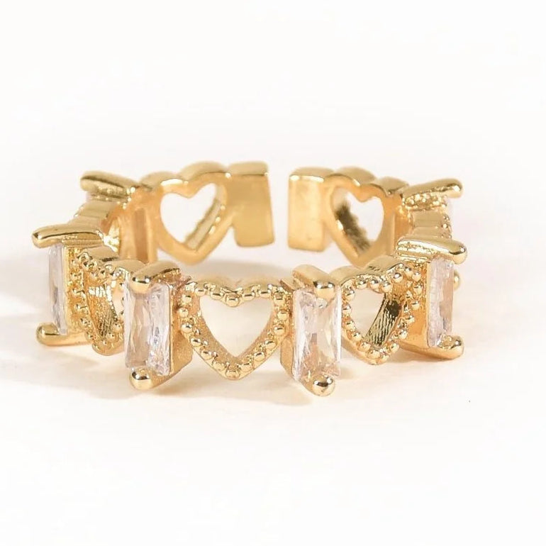Gold-toned open ring featuring multiple heart-shaped cutout details and rectangular clear crystal accents arranged around the band.