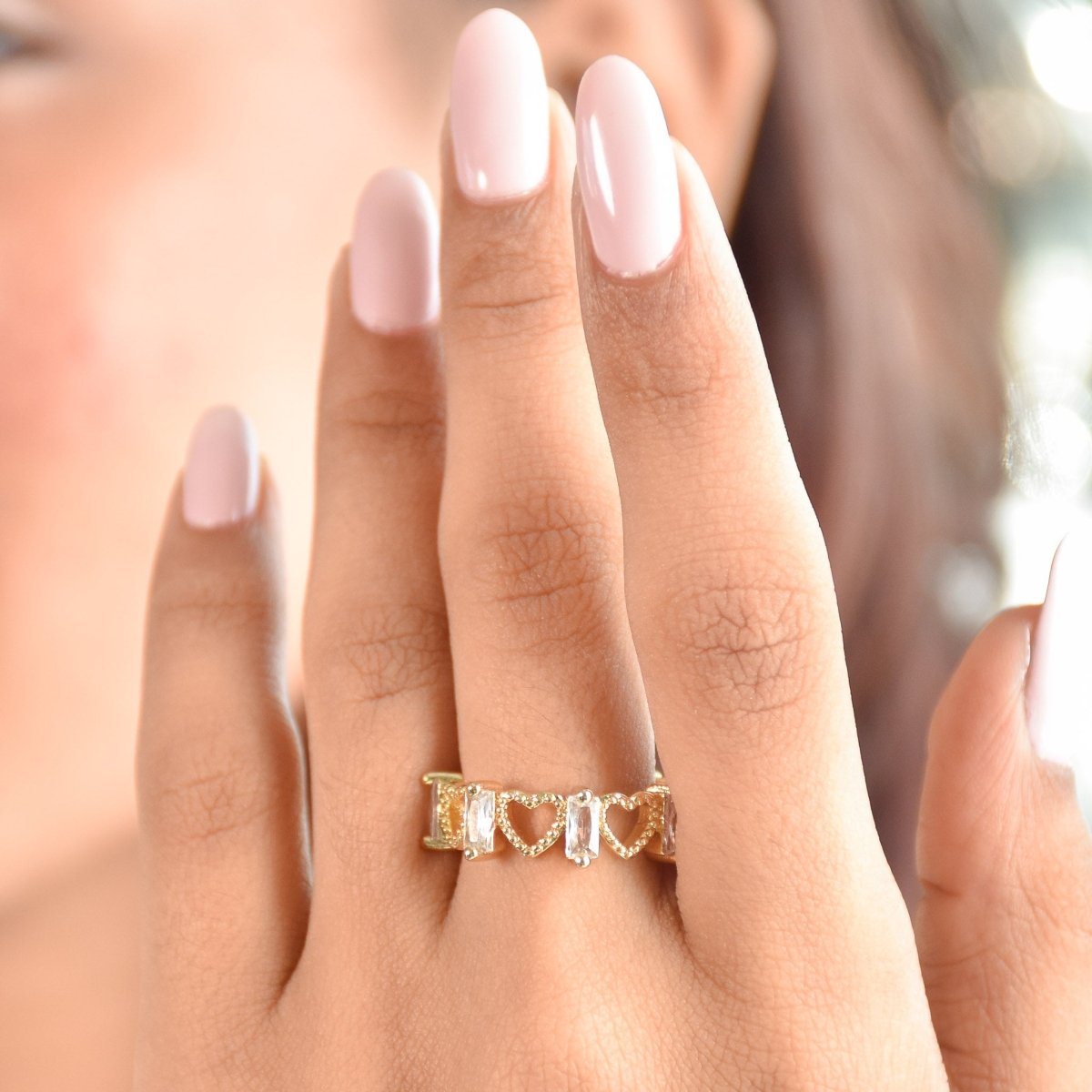 Elegant golden ring with heart motifs, sparkling baguette-cut stones, and an adjustable anti-tarnish finish, perfect for timeless styling, stacking, and everyday sophistication.