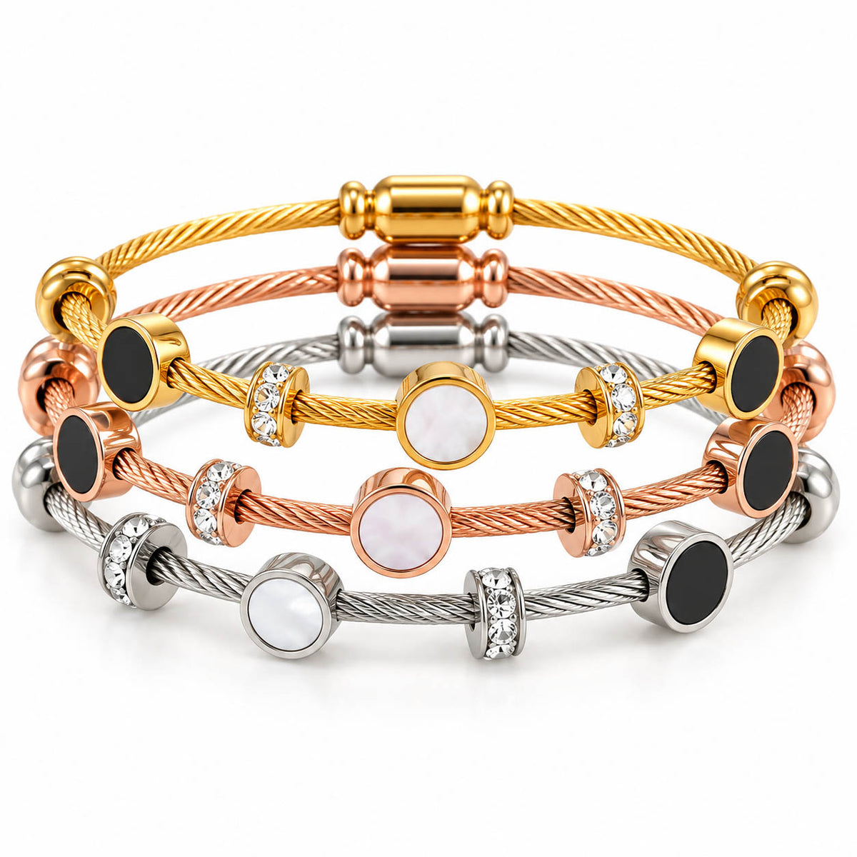 A studio shot of a multi-tone luxury bracelet stack showcasing layered cable wire strands in gold, rose gold, and silver finishes. The set is accented with circular stations featuring black enamel and white mother-of-pearl inlays, interspersed with sparkling crystal-paved ring spacers.
