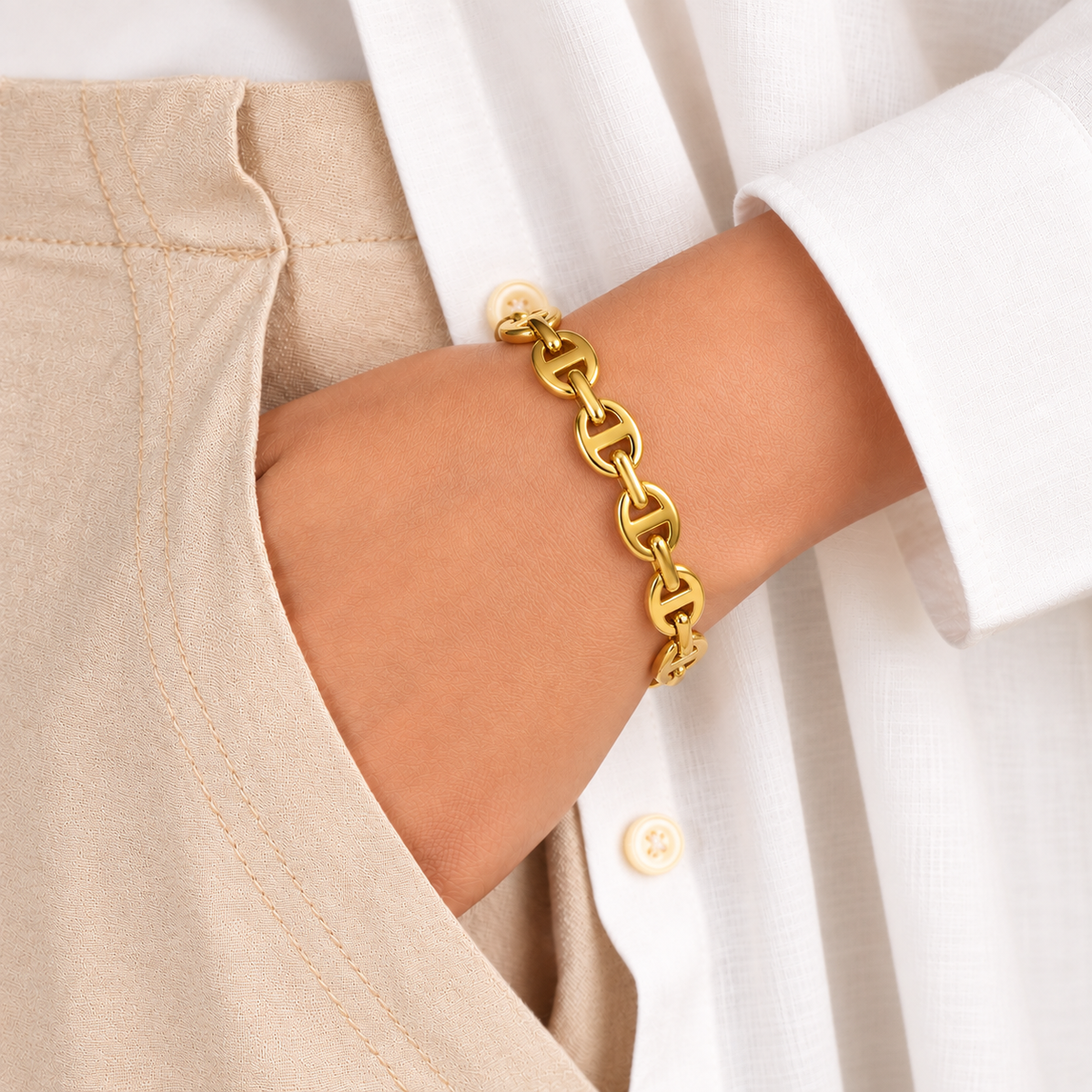 Gold-tone chain-link bangle bracelet worn on a wrist with a white shirt and beige outfit.