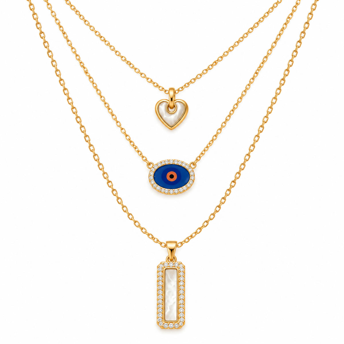 A product photo of a layered gold-tone necklace set featuring a heart pendant with white mother-of-pearl inlay, a horizontal oval evil eye charm framed in crystals, and a rectangular pendant with a mother-of-pearl center and a rhinestone border.