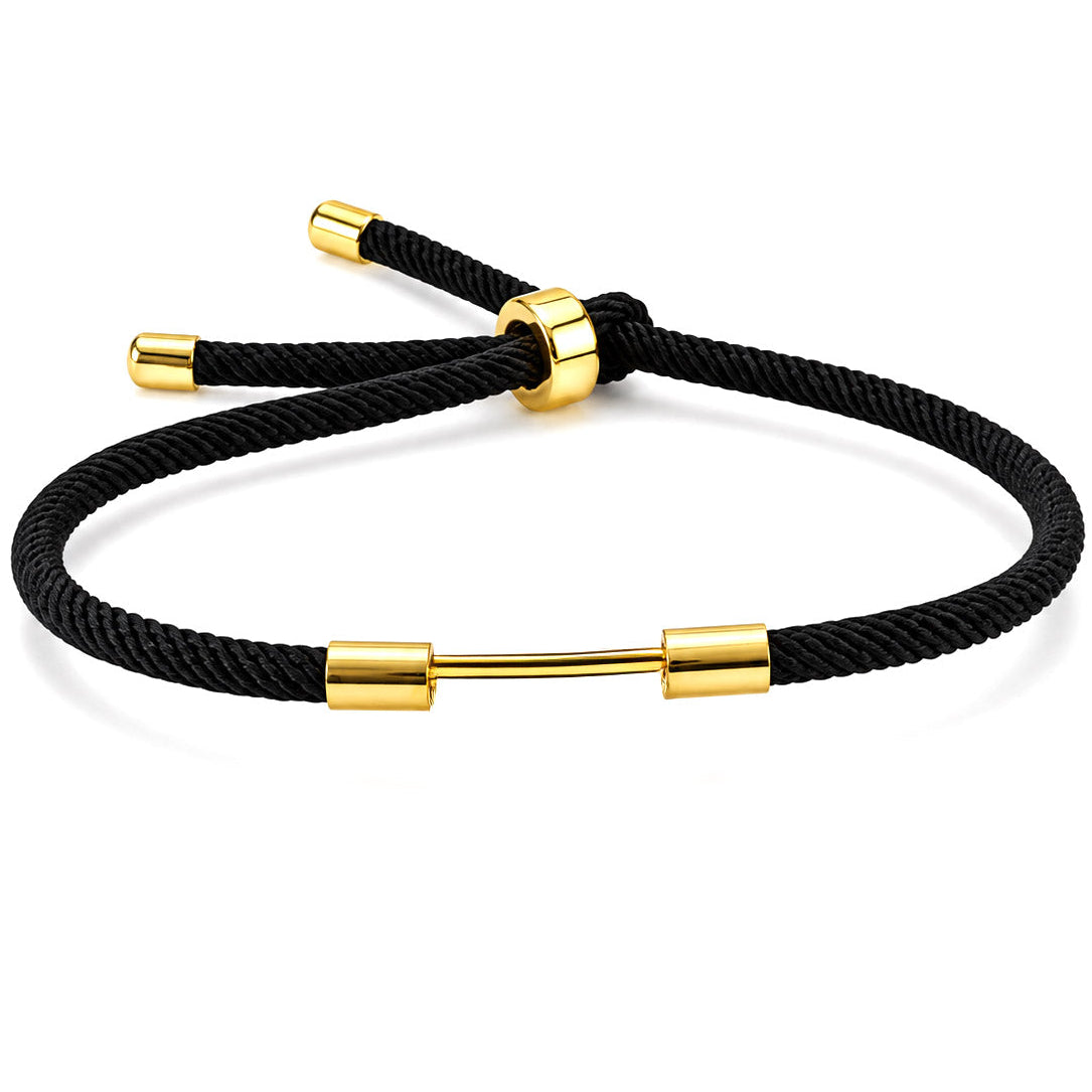 Black woven cord bracelet with a polished gold dumbbell charm and adjustable slider bead on a white background.