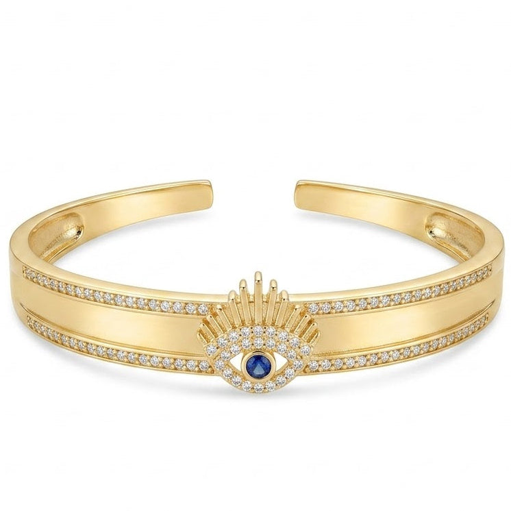 Anti-tarnish yellow gold open cuff bracelet featuring a central sunburst eyelash evil eye motif with a blue sapphire crystal center, surrounded by clear pavé cubic zirconia borders on a smooth flat band.