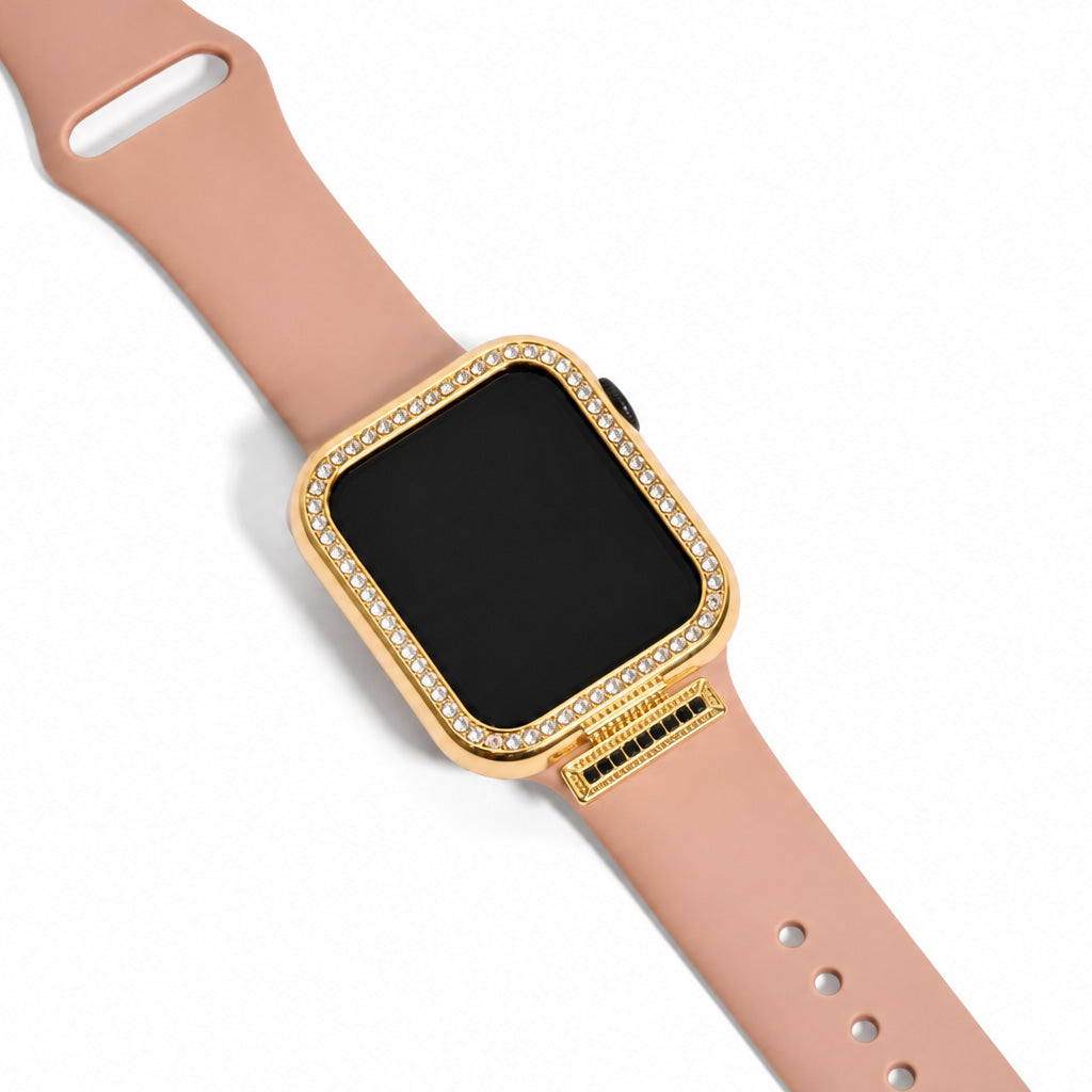 Zoomed-out view of a gold-tone smartwatch case embellished with clear sparkling stones and a detailed gold watch charm, paired with a blush pink watch strap on a clean white background.