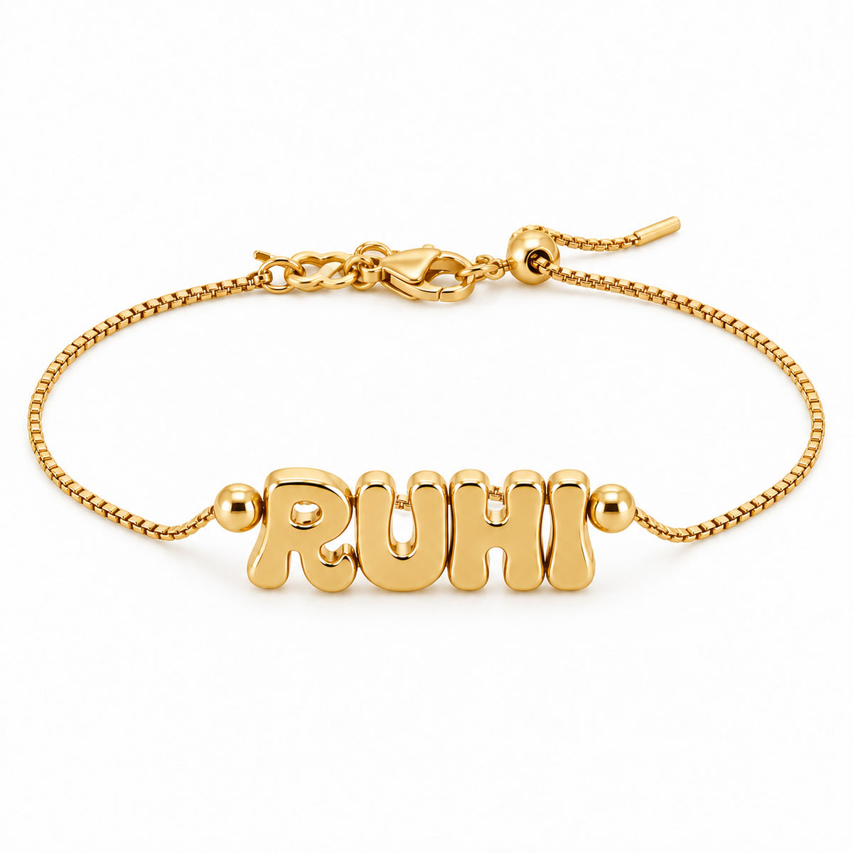 A product studio photograph of a gold-toned adjustable box-chain bracelet featuring chunky, puffed bubble-letter charms spelling "RUHI" flanked by smooth gold beads, presented against a clean white background with its lobster clasp and sliding bead adjuster.