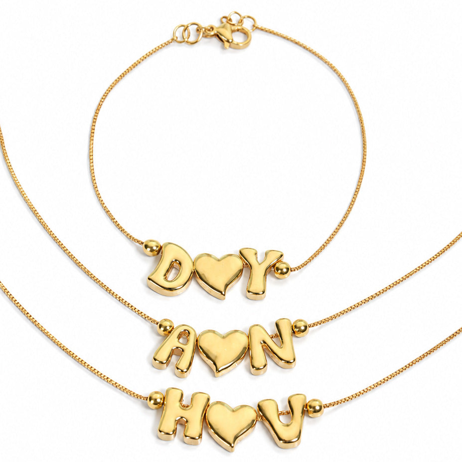 Gold-plated personalized bracelets featuring D♥Y, A♥N, and H♥U initial-and-heart charms, displayed on a clean white background.