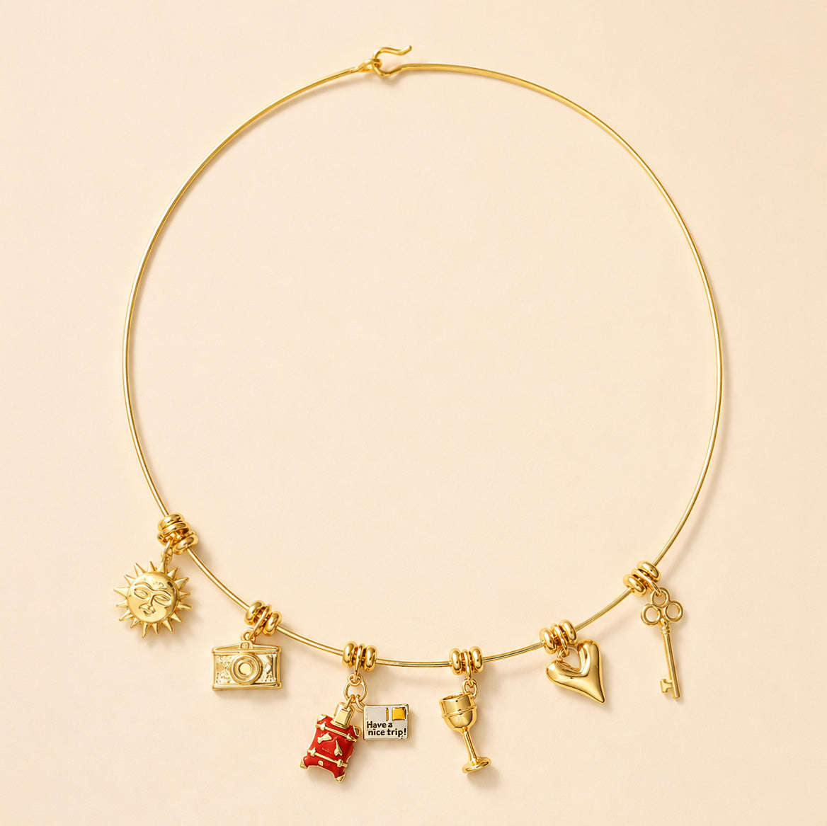 Gold charm choker necklace featuring a sun charm, camera charm, red suitcase charm, quote charm, cocktail glass, heart charm, and key charm.