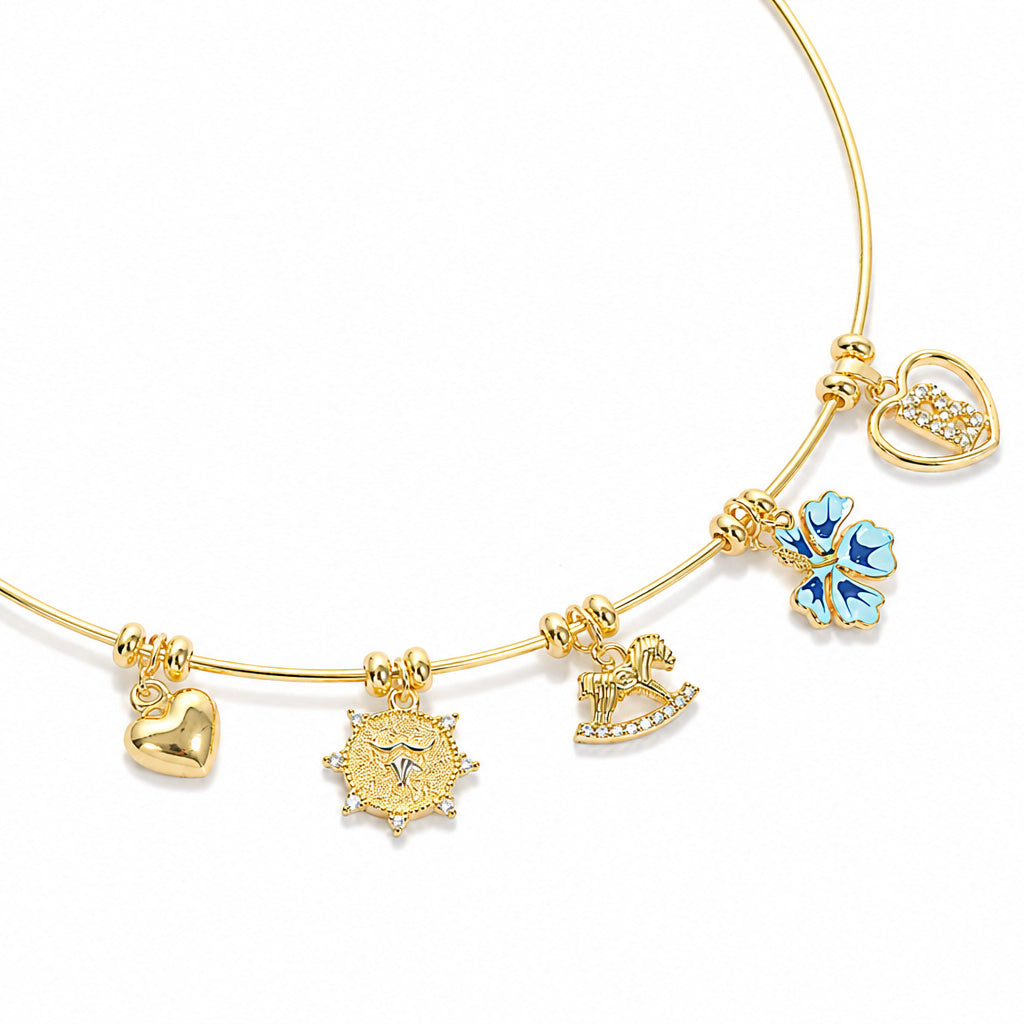 Gold charm necklace on a clean white background, featuring a heart charm, detailed sun charm, sparkling horse charm, blue flower charm, and crystal-studded letter charm.