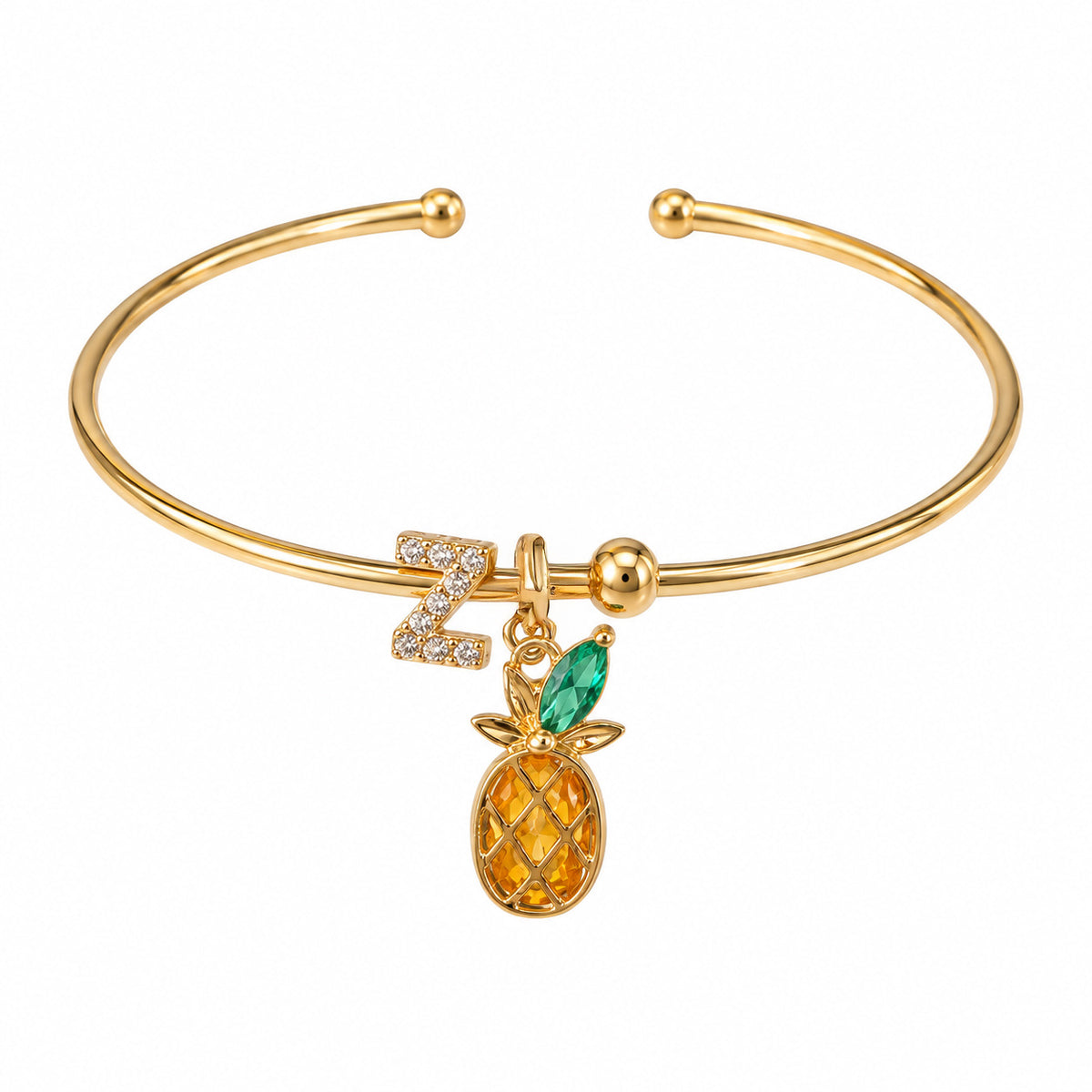 Gold-tone open cuff bracelet featuring a sparkling letter “Z” charm and a dangling pineapple charm with a green leaf and golden fruit, displayed on a clean white background.