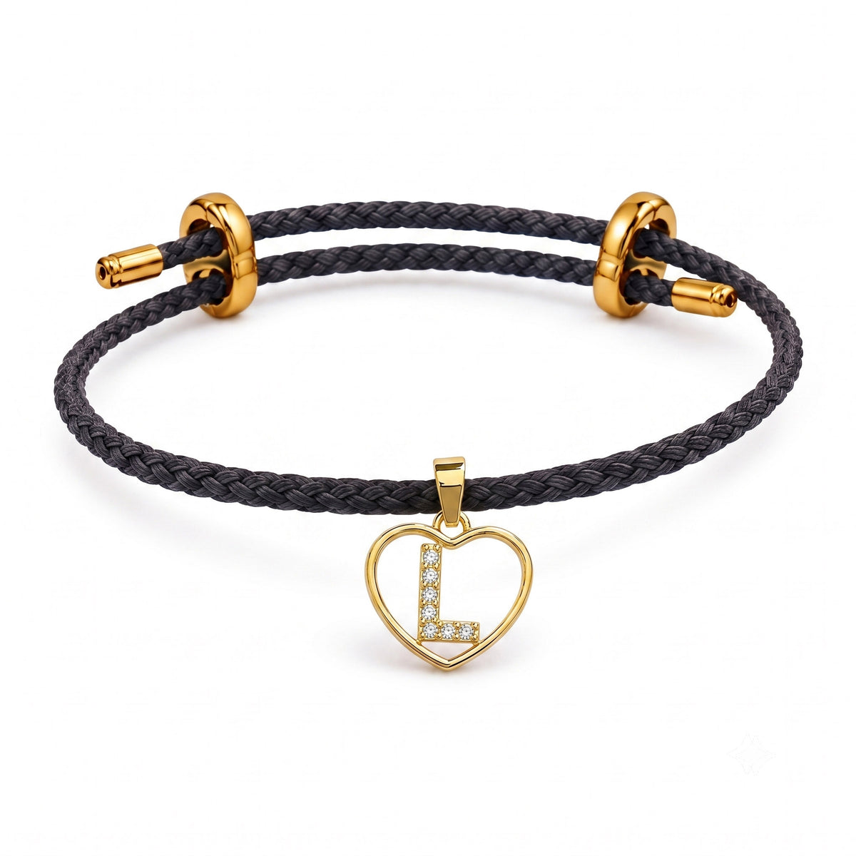 This is a dark braided cord bracelet with an adjustable gold clasp and a sparkling heart-shaped initial charm featuring the letter “L.