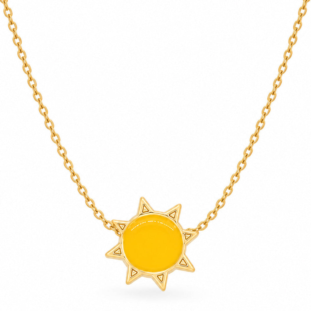 A studio shot of a thin gold link necklace centered with a vibrant yellow sun charm surrounded by small pointed rays.