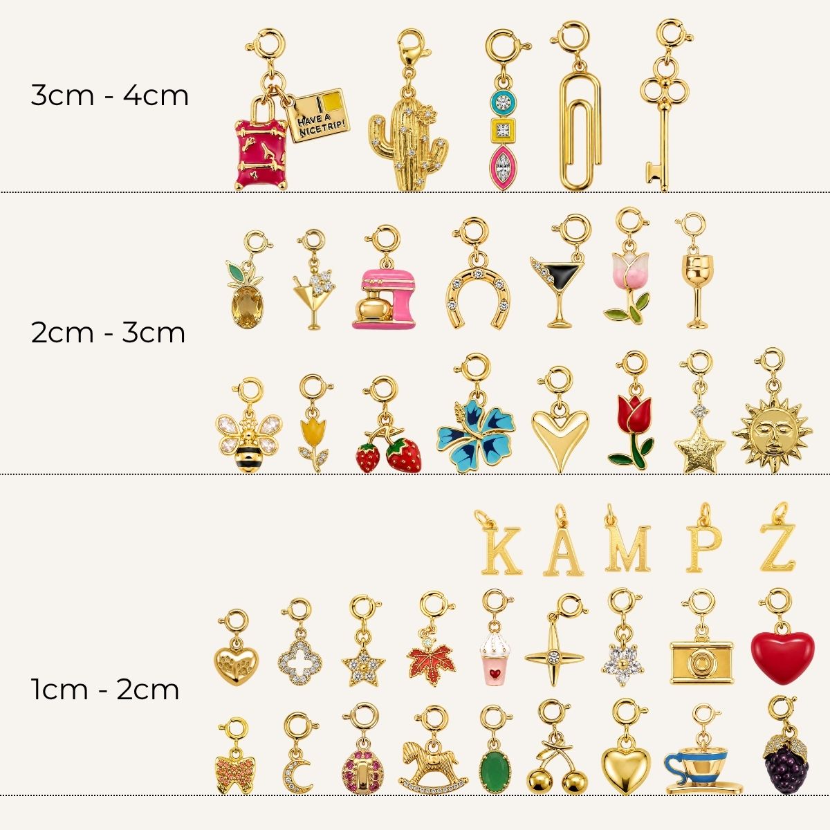 A collection of gold-toned charms with spring-ring clasps organized by size ranges from 1 cm to 4 cm. The assortment features various designs such as travel accessories, food and drinks, animals, flowers, celestial symbols, everyday objects, and uppercase alphabet letters embellished with colorful enamel and crystal details.