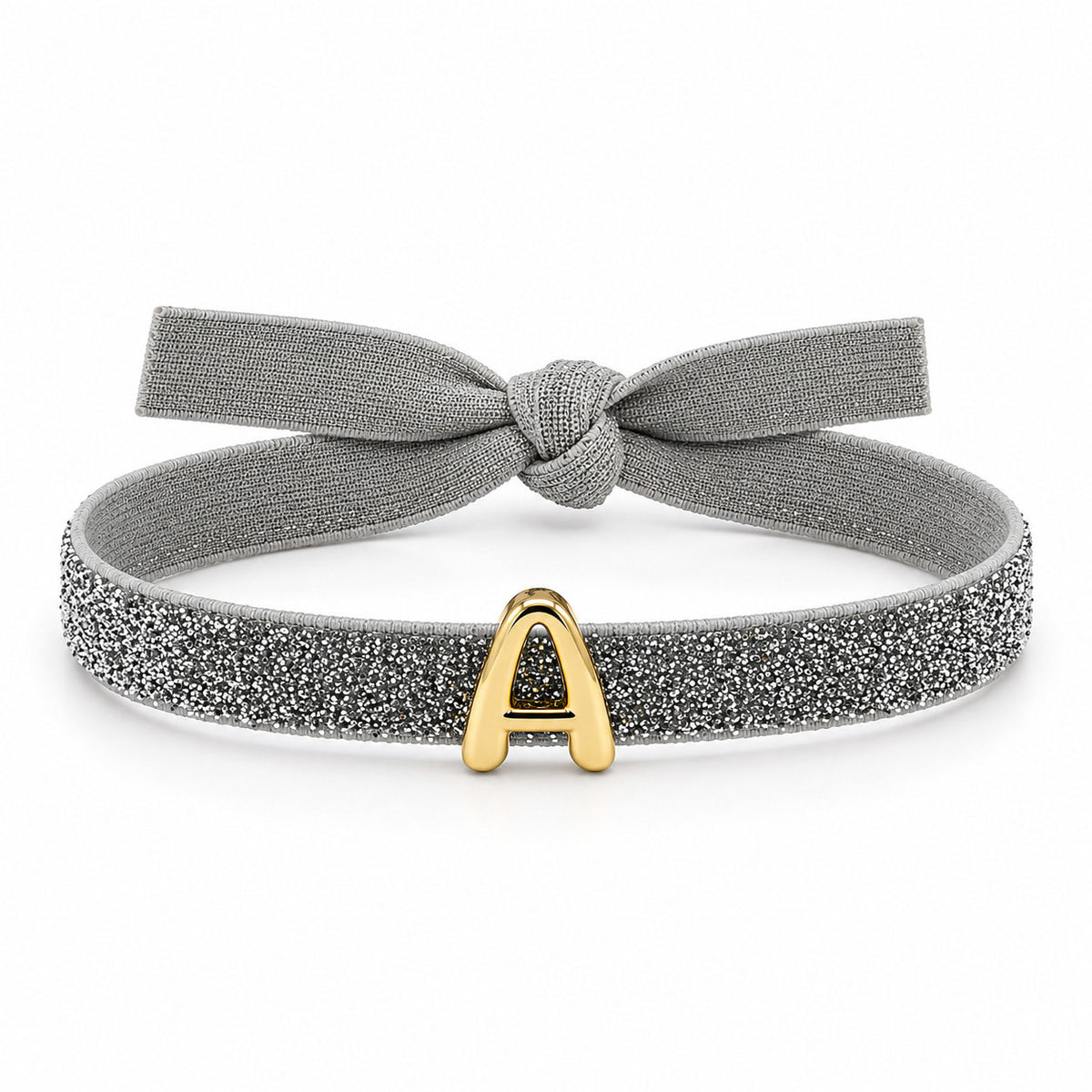 Silver glitter bracelet with a matching fabric bow and a gold “A” initial charm, displayed on a clean white background.