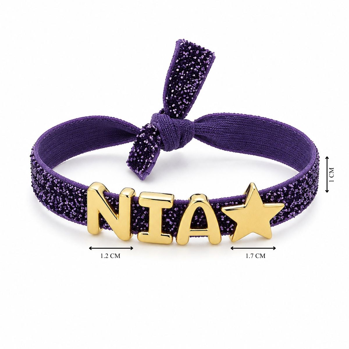 Purple shimmery bow headband featuring gold-tone NIA letter charms and a gold star charm, with the band width measuring 1 cm, the N charm approximately 1.2 cm wide, and the star approximately 1.7 cm wide.