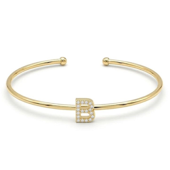 Elegant gold-tone adjustable open cuff bangle featuring a pavé crystal-studded letter B centerpiece. The personalized initial bangle has a sleek polished finish with rounded ball ends and is displayed on a clean white background, making it perfect for everyday wear, stacking, gifting, and personalized jewellery collections.