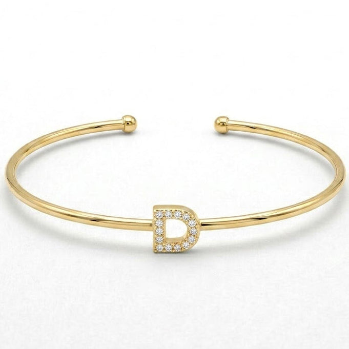 Elegant gold-tone adjustable open cuff bangle featuring a pavé crystal-studded letter D centerpiece. The personalized initial bangle has a sleek polished finish with rounded ball ends and is displayed on a clean white background, making it perfect for everyday wear, stacking, gifting, and personalized jewellery collections.