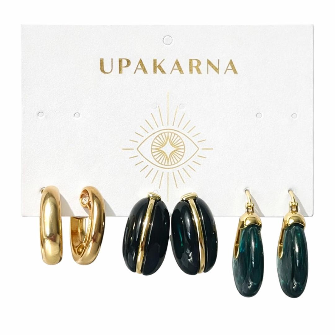 Three-pair earring stack featuring deep emerald green resin hoops, gold half-hoops, and a crystal bow earring with a large drop pearl on a branded card.