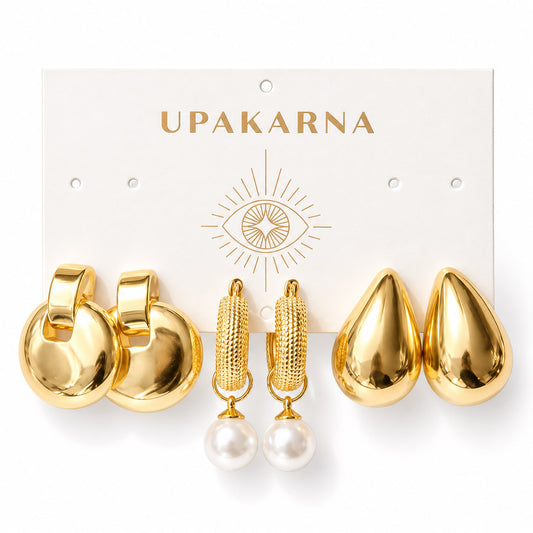 Three pairs of gold-plated statement earrings displayed on an Upakarna jewellery card, featuring bold round disc drop earrings, textured hoop earrings with pearl drops, and oversized teardrop-shaped stud earrings, arranged on a clean white background with a premium polished finish.