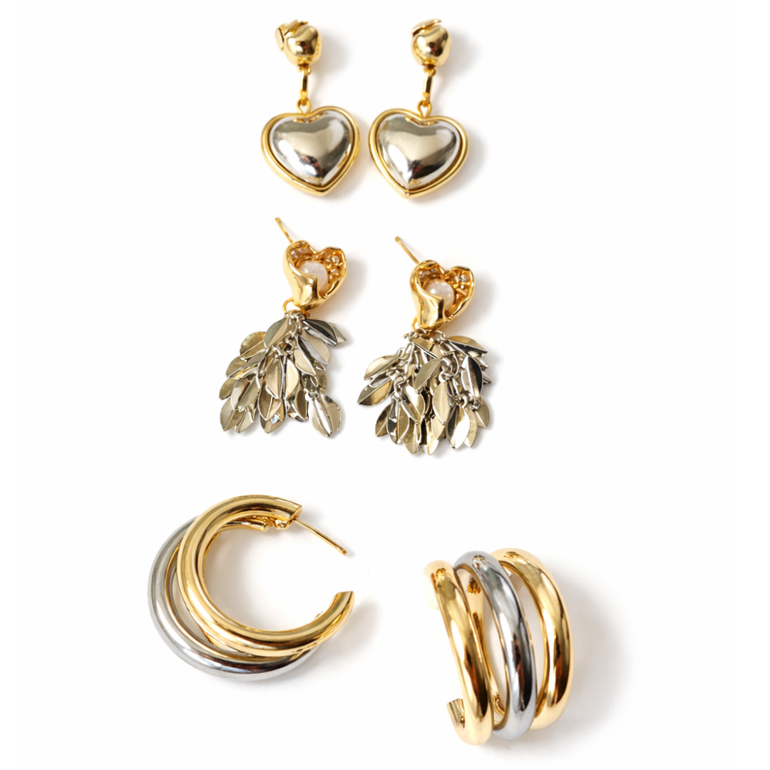 Gold earring stack with triple hoops, heart drop earrings, and cascading leaf design earrings with crystal details