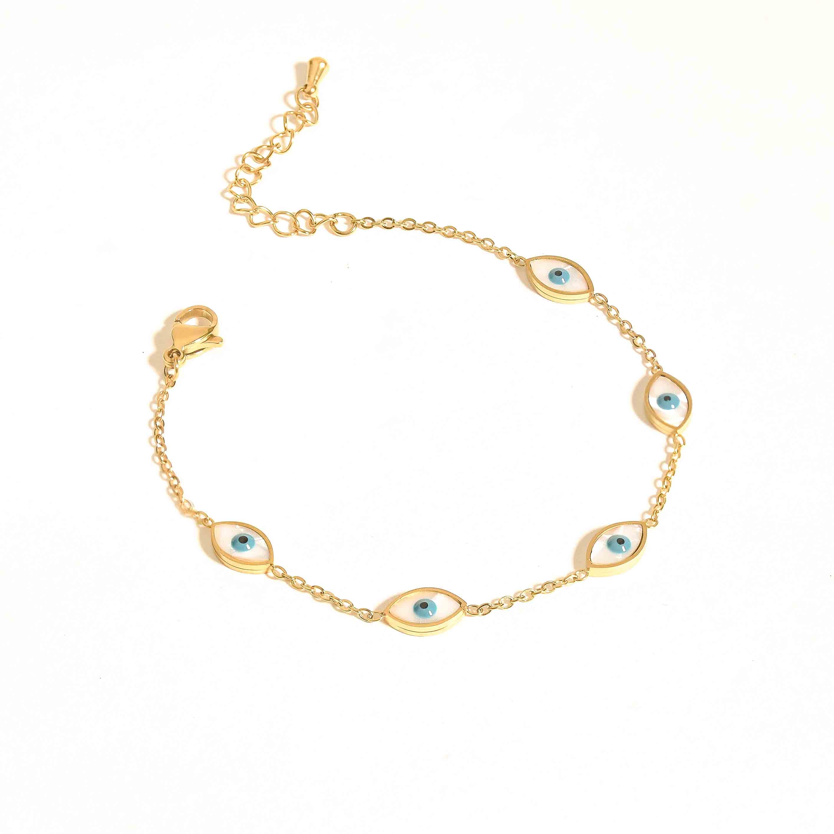Gold bracelet stack with heart, evil eye, and hamsa designs, blending playful charm, protective symbolism, and refined sparkle.