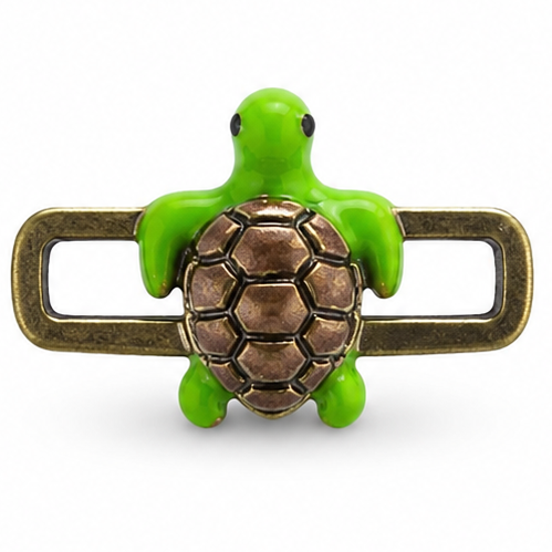 Detailed green turtle jewellery charm featuring a glossy bright-green turtle with a rounded head, small black eyes, four short flippers, and a raised bronze-brown shell with an intricate hexagonal and segmented pattern. A textured antique-gold rectangular loop extends horizontally behind the turtle on both sides.