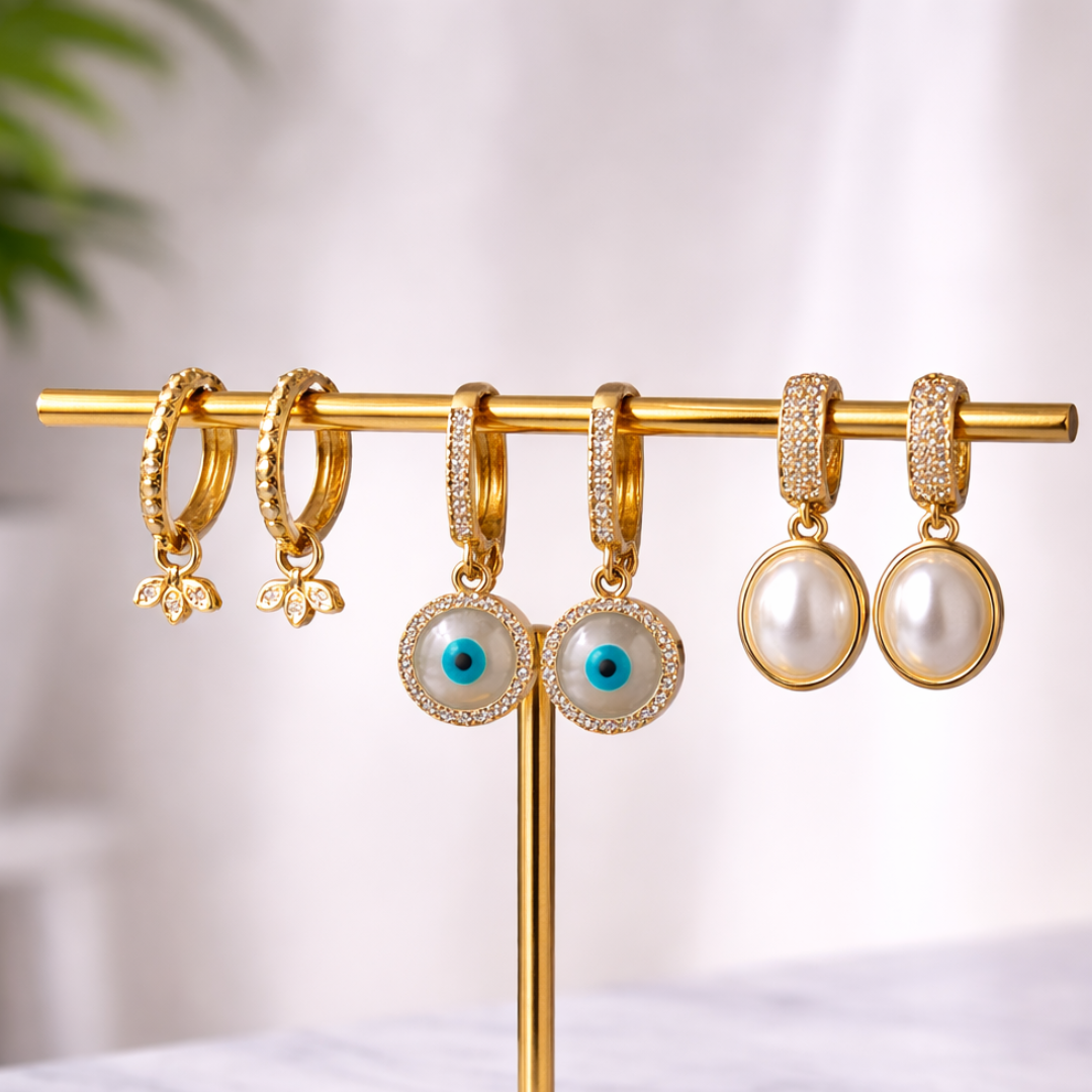 Gold earring stack with diamond petal, pearl and evil eye drops