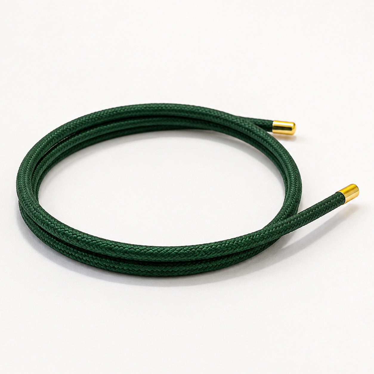 Emerald green magnetic mesh wrap bracelet with polished gold end caps coiled on a white background.