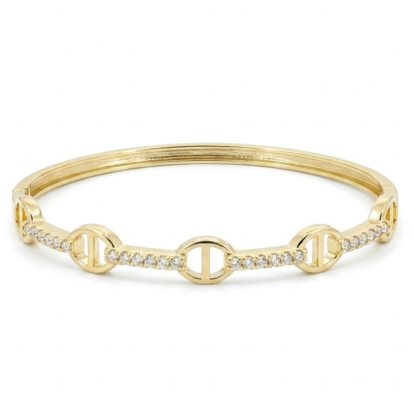 Anti-tarnish yellow gold hinged bangle bracelet featuring alternating mariner anchor link stations and pavé cubic zirconia segments, set against a solid white background.