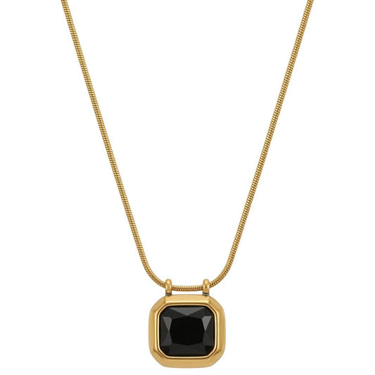 A gold necklace with a delicate snake chain holding a square-cut black gemstone pendant with faceted edges. The black stone is encased in a smooth, thick gold bezel frame, centered on a plain white background with a dark frame around the image.