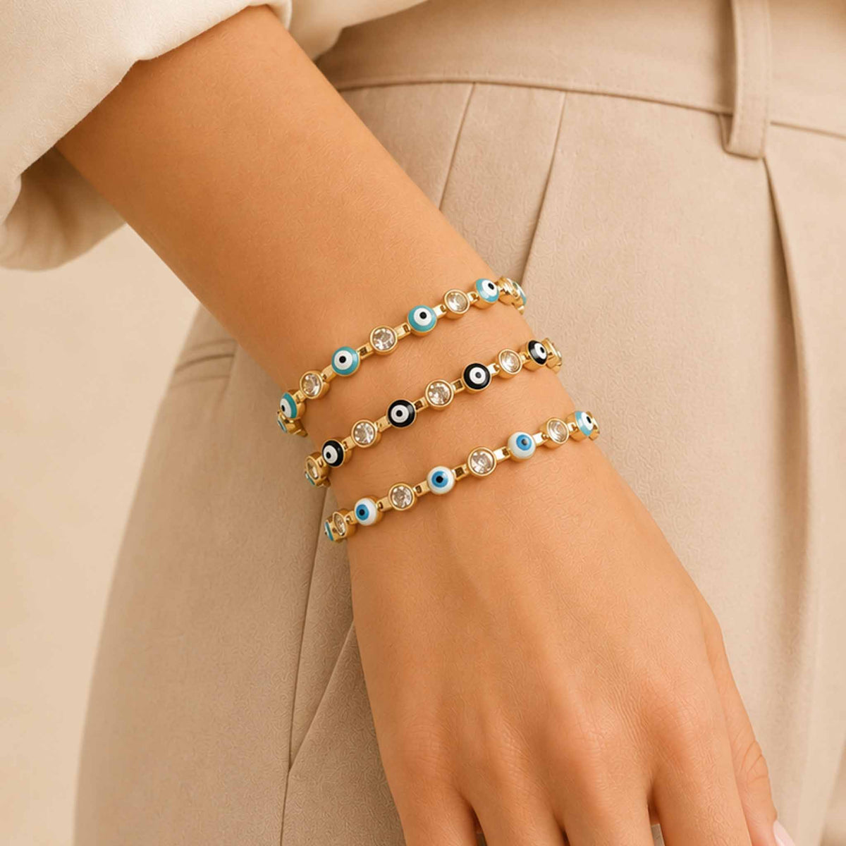 Mystic Blue Stack featuring three gold Evil Eye cuff bangles in light blue, black, and white, styled on a woman's wrist with a neutral outfit.