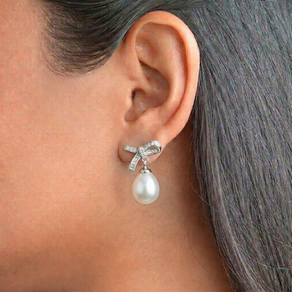 Pearl Ribbon 925 Sterling Silver Earrings featuring sparkling pave-set ribbon bow studs adorned with lustrous teardrop pearl drops