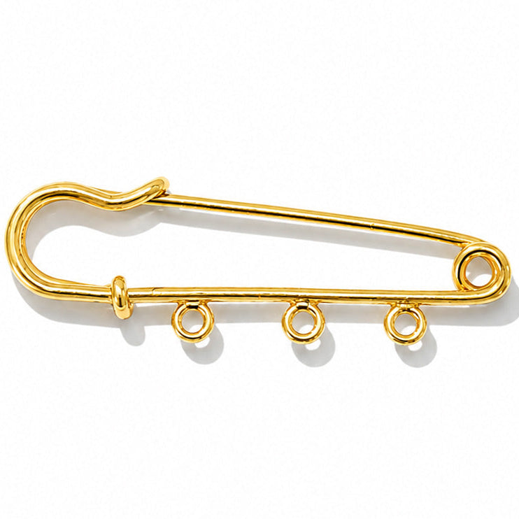 Gold-tone safety pin brooch with three circular charm attachment rings along the lower bar, shown on a clean white background with soft natural shadows.