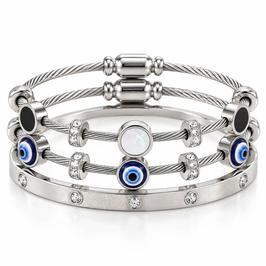 A product photo of a stacked set of silver-tone bracelets featuring twisted cable wire strands, solid black disks, white mother-of-pearl stations, blue-and-white evil eye beads, and a crystal-set bangle.