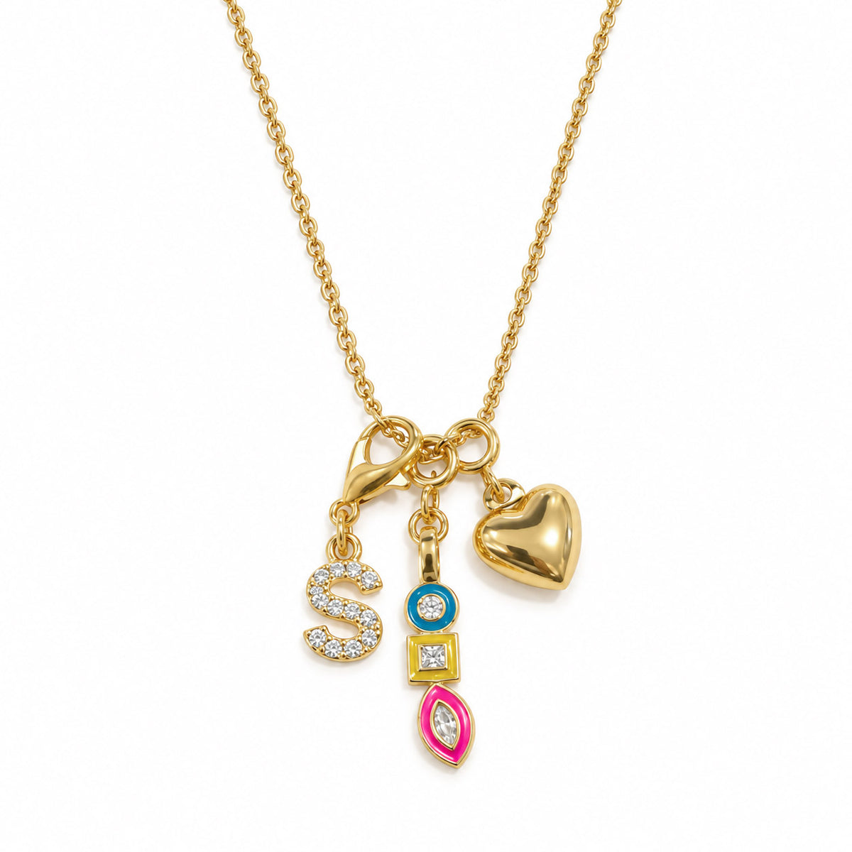 Gold-plated charm necklace featuring a sparkling “S” initial, a colorful gemstone charm, a pink marquise-shaped charm, and a polished gold heart charm on a delicate chain, displayed on a clean white background.