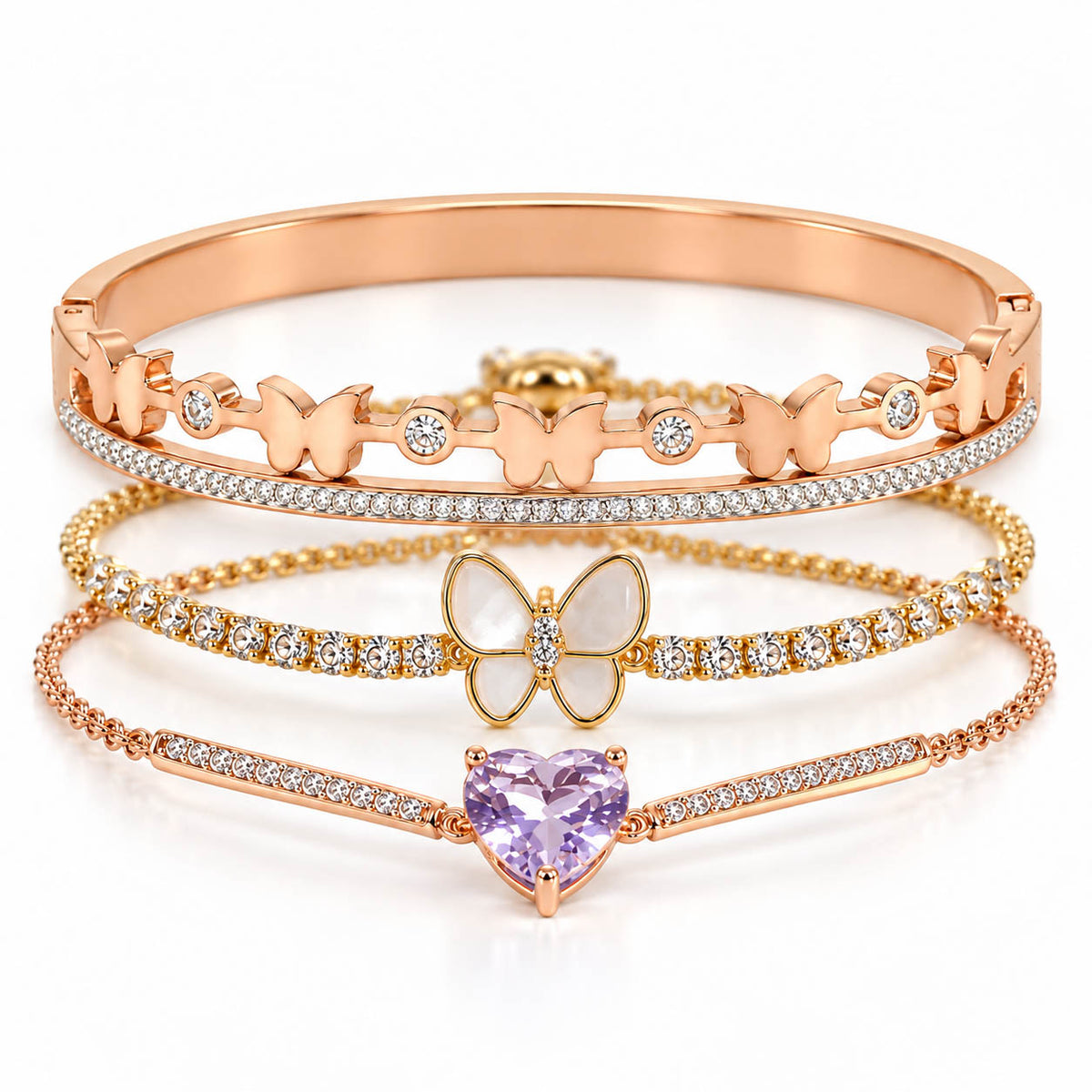 A studio shot of a curated luxury rose gold bracelet stack showcasing three distinct pieces: an upper hinged bangle adorned with small butterflies and crystal stones, a middle crystal-paved chain featuring a central white mother-of-pearl butterfly pendant, and a lower thin link chain centered with a faceted pastel purple heart-shaped crystal.