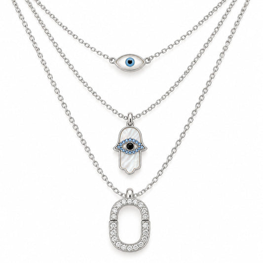 Upakarna silver layered necklace set featuring an evil eye chain, Hamsa evil eye pendant, and crystal pavé link pendant on a clean white background.