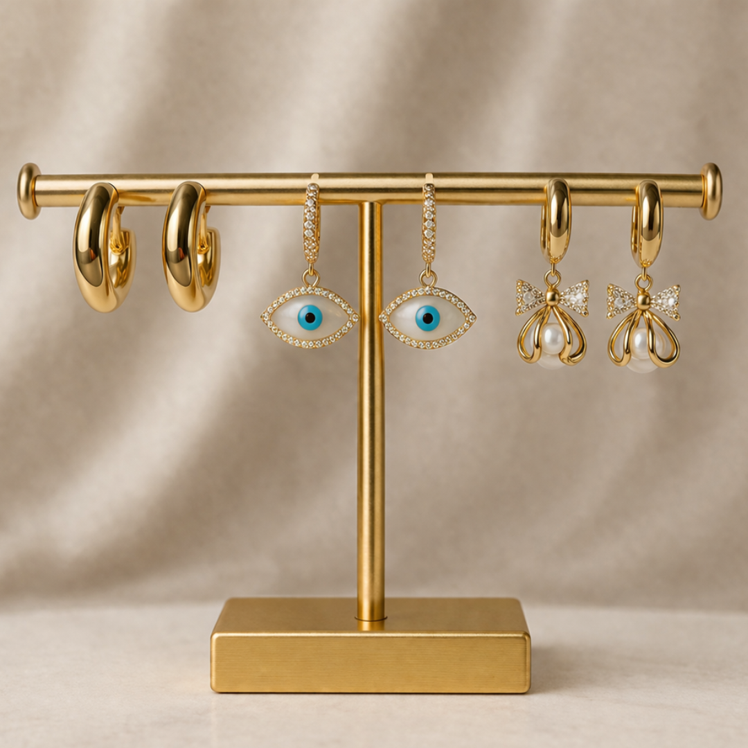 Golden earrings set featuring chunky hoops, pearl bow drop earrings, and evil eye charm drops