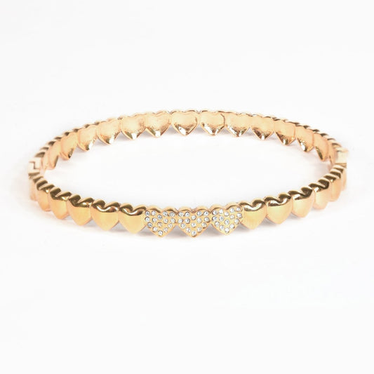 Heart motif bangle with pavé crystal accents and an anti-tarnish finish, available in gold and silver, perfect for everyday wear, romantic styling, and elegant stacking.