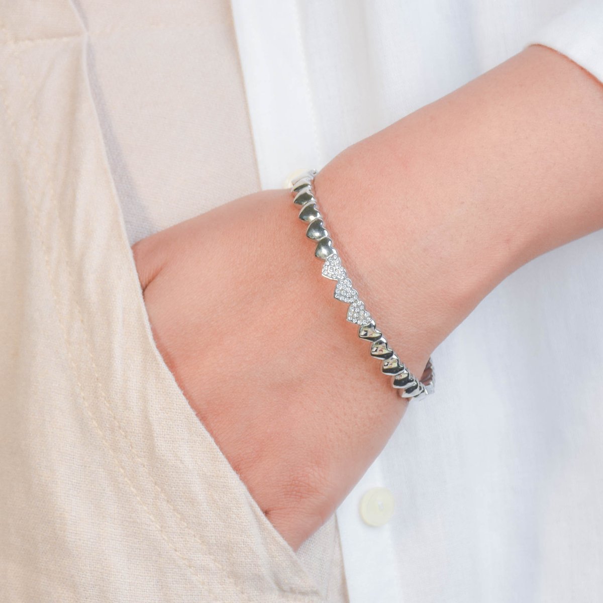 Heart motif bangle with pavé crystal accents and an anti-tarnish finish, available in gold and silver, perfect for everyday wear, romantic styling, and elegant stacking.