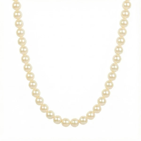 The image shows a classic pearl necklace made of evenly sized, cream-white round pearls arranged in a simple U-shaped strand. It is photographed against a clean white background with soft, minimal lighting.