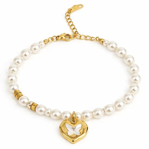 Gold-tone pearl bracelet featuring a strand of white pearl-like beads with small gold spacer beads and a central heart-shaped charm with a white butterfly detail.