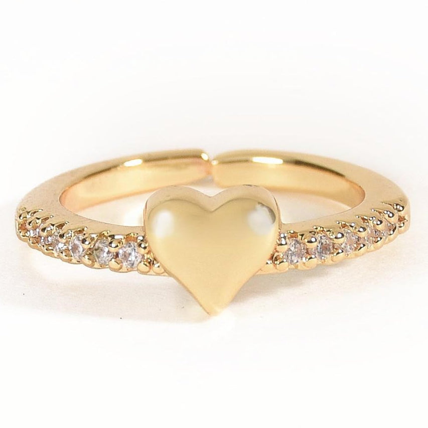 Gold-tone heart ring featuring a smooth, polished heart-shaped centrepiece and a band embellished with sparkling clear stones. A delicate, romantic design perfect for everyday styling, stacking, or gifting.