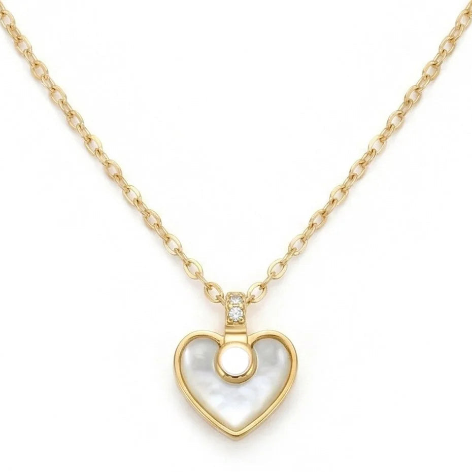 The image shows a delicate gold-toned necklace with an oval-link chain and a heart-shaped pendant featuring a polished mother-of-pearl center, gold border, and a small crystal-accented connector. The necklace is photographed against a clean white background.