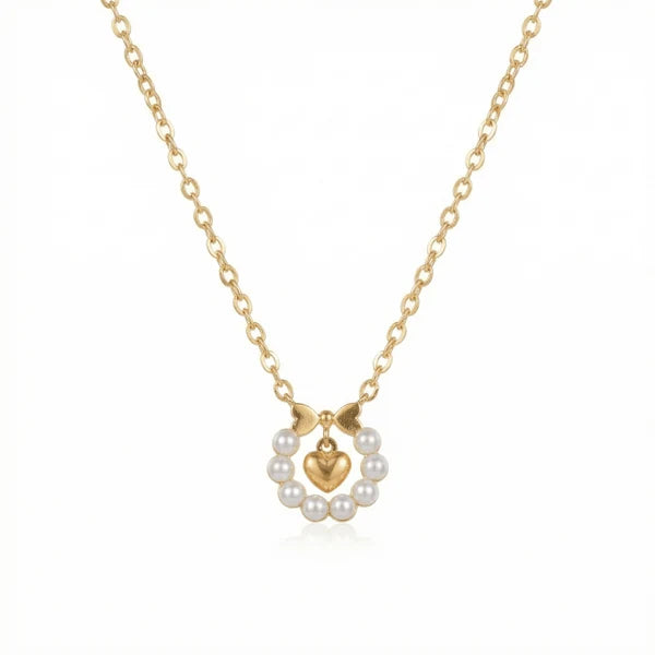 The image shows a delicate gold-toned necklace with a small heart pendant surrounded by a circular arrangement of white pearls. Two small gold bow-like elements sit above the pearl circle, creating a feminine, elegant design. It is photographed against a clean white background.