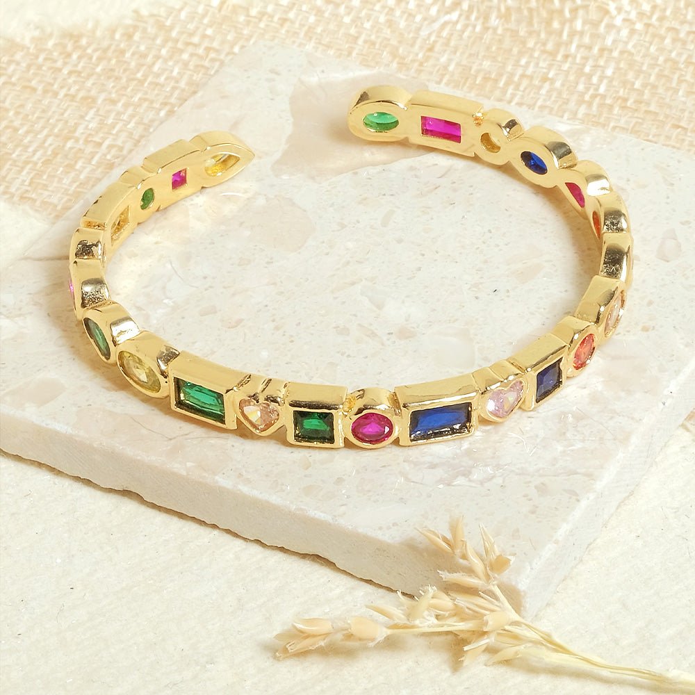 Stylish multi-colored cuff bangle with heart, pearl, and geometric charm detailing and an adjustable anti-tarnish finish, perfect for playful stacking, everyday glam, and trendy statement styling.