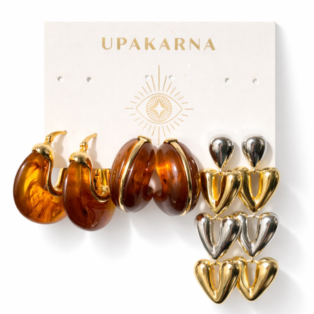 Warm amber tone earring stack with glossy resin hoops and bold triple heart gold earrings