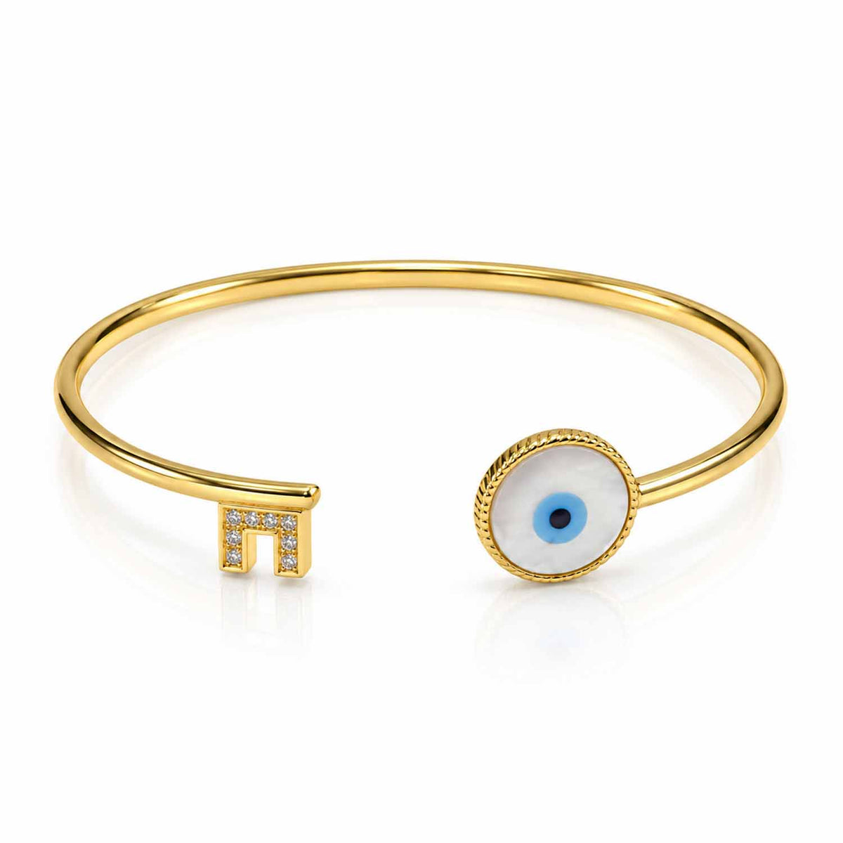 Gold open cuff bangle featuring a round blue evil eye centerpiece with a textured gold border and a crystal-studded geometric end detail, displayed on a clean white background.