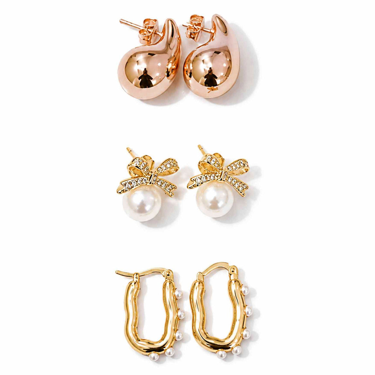 Gold, rose gold and pearl earring stack featuring teardrop studs, pearl bow earrings and pearl-lined hoops on a clean white background.